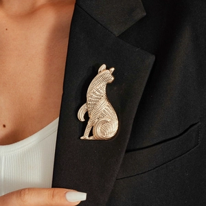 Detailed view of a vintage gold dog brooch with textured etching on a black blazer lapel