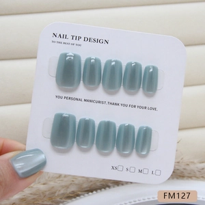 Faux ongles œil de chat vert émeraude courts et carrés présentés sur carte de marque
