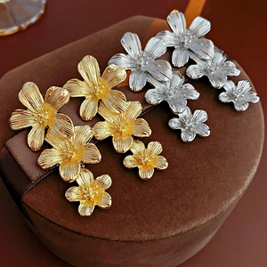 Macro shot of gold and silver flower drop earrings with textured petals on suede