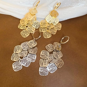 Detailed close-up of geometric hollow tassel earrings in gold and silver finishes