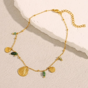 Détail de la chaîne en acier plaqué or 18K avec pendentifs coquillages et perles vertes
