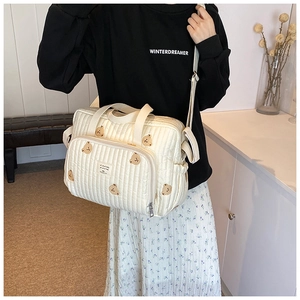 Sac à langer matelassé blanc crème avec broderie ours brun porté en bandoulière