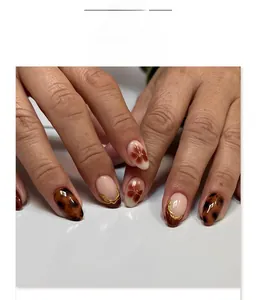Detail of amber tortoiseshell and almond press-on nails with vintage floral patterns