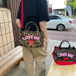 Leopard and camouflage tote bags with LOVE ME print shown in an outdoor street setting