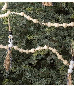 Close-up of rustic Christmas wood bead garland with snowman charms on pine branches