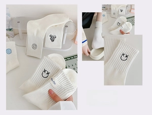 Detailansicht weißer gerippter Wadenstrümpfe mit niedlicher Stickerei und Textiletikett