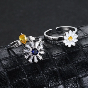 Primer plano de anillos giratorios de girasol y margarita con gemas azules y amarillas.