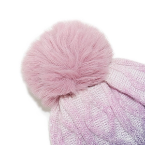 Detail der Strickmütze mit Farbverlauf in Pink-Violett, großem Kunstfellbommel und Zopfmuster