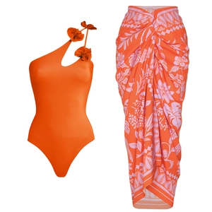 Detail of orange one-shoulder swimsuit with 3D floral accent and matching tropical wrap skirt