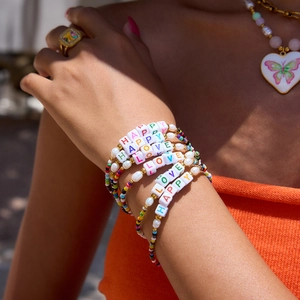 Close-up of stacked colorful beaded bracelets with LOVE and HAPPY letter charms