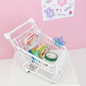 Miniature white iron shopping cart organizer with colorful tapes on a pink background