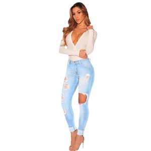 Women's skinny ripped jeans in light blue paired with a slim-fit V-neck beige sweater