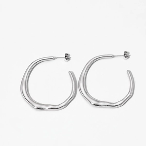 Macro shot of silver irregular hoop earrings with smooth polished metallic finish