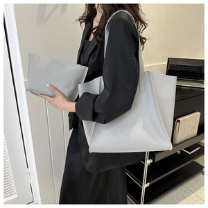 Close-up of light gray large capacity tote bag and matching pouch on a black blazer