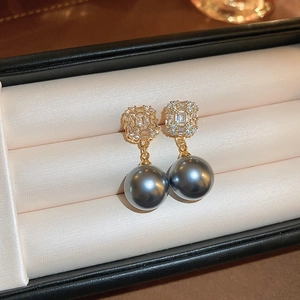 Détail de boucles d'oreilles dorées avec perles et cristaux dans un écrin de luxe