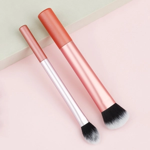 Detailed view of dual-size makeup brushes with coral orange handles and soft synthetic bristles