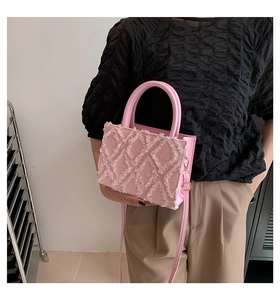 Detail of pink square handbag featuring brushed textured grid and cylindrical top handle