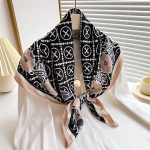 Detailed view of floral and geometric print silk scarf draped on a white hanger