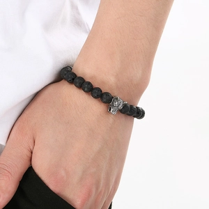 Close-up of 8mm black lava stone bracelet with a silver wolf head on a male wrist