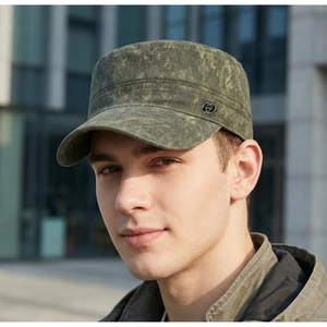 Close-up of a vintage washed green military flat top cap for men worn outdoors.