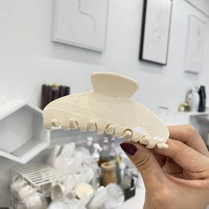 Makro-Detail einer großen cremefarbenen Haarklammer aus Acetat mit glattem Finish