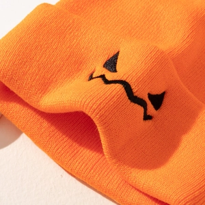 Close-up of orange Halloween knit beanie featuring black embroidered pumpkin face pattern