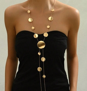 Detail shot of long golden geometric disc chain necklace styled on a black garment