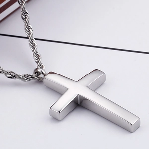 Gros plan d'un pendentif croix en acier inoxydable argenté avec une chaîne torsadée