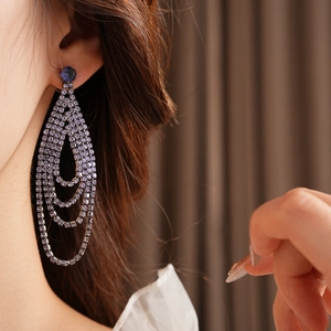 Detail of elegant teardrop tassel earrings with dark blue stones and purple rhinestones