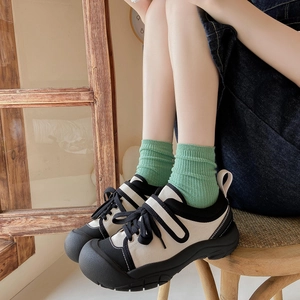 Japanese style green ribbed crew socks paired with beige canvas sneakers for casual wear