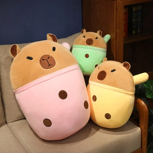 Three capybara plush toys in pink, yellow, and green milk tea cups on a cozy sofa