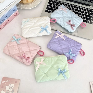 Quilted cosmetic bags in pastel colors with bow accents and zip closure