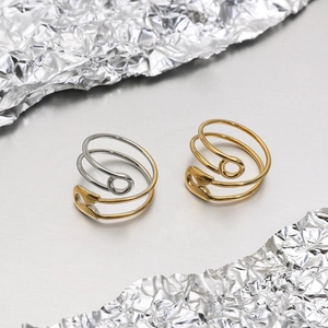 Detail of gold and silver paperclip spiral rings on a modern matte surface