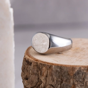 Minimalist wide polished stainless steel ring displayed on a natural wooden stump pedestal