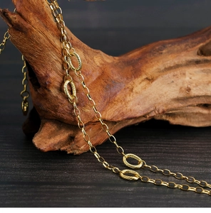 Close-up of a polished golden necklace chain with interlocking oval links on wood