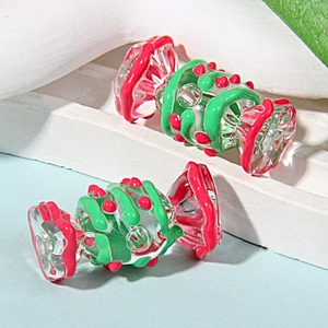 Primer plano de dos cuentas de vidrio en forma de caramelo con detalles pintados en rojo y verde