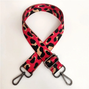Close-up of red leopard print wide bag strap with gunmetal swivel hooks and adjustable buckle