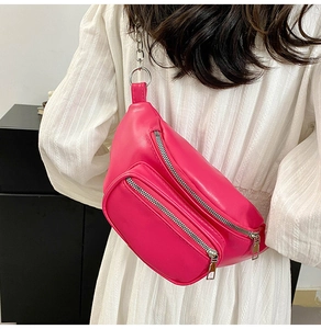 Detail of fuchsia PU leather crossbody chest bag with silver chain strap on a white dress