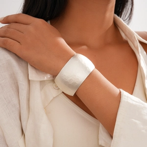 Detail of silver wide cuff bracelet featuring handcrafted hammered texture on a female wrist
