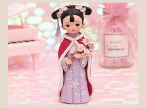 Macro detail of doll in red cloak and purple embroidery with floral hair ornament
