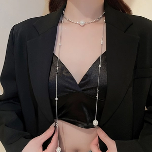 Close-up of a layered silver necklace with pearls over a black blazer and satin inner
