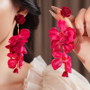 Détails des pétales de fleurs en tissu rouge et des éléments en métal doré de la boucle