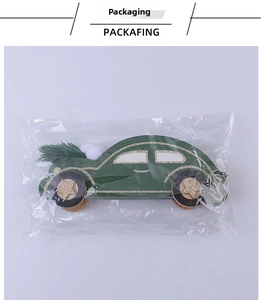Gros plan d'une décoration voiture en bois verte avec sapin sous emballage plastique