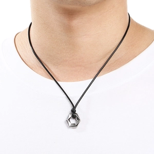 Detail shot of a silver hexagonal pendant on black cord worn by a male model