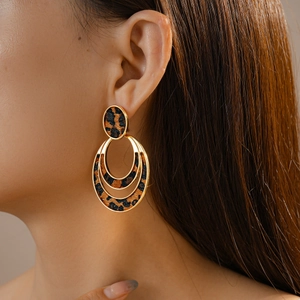 Close-up of model wearing gold geometric leopard print earrings with hollow circles