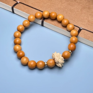 Detail of sandalwood bead bracelet with a finely carved lotus charm and silver spacers