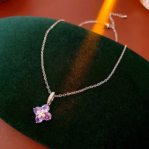 Gros plan d'un pendentif trèfle argenté avec zircon violet sur support en velours