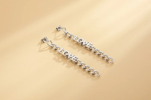 Detail of silver long chain earrings featuring the word LOVE with tassel elements