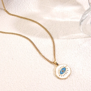 Elegant gold evil eye pendant necklace with white and blue enamel on textured background