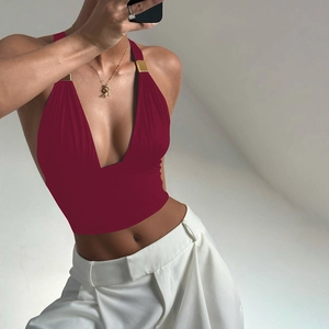 Detail eines weinroten Neckholder-Tops mit tiefem V-Ausschnitt und Goldmetallschnallen